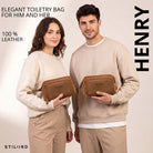 Dois modelos seguram necessaire Henry em couro tan, vista frontal com alça de pulso e gravação STILORD visível